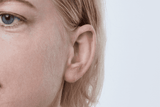 Oticon More Hörgerät, Modell miniRITE R, Farbe Hellgrau, Foto von vorne in einem Winkel von 45°, Nahaufnahme am Ohr, Frau Hörgeräte mit unbeschränktem Service Auzen